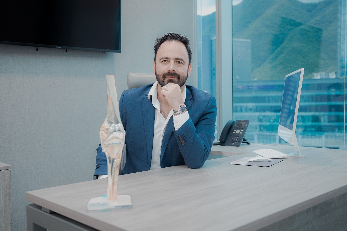 El Dr. José Andrés Acosta en su consultorio con un modelo de rodilla